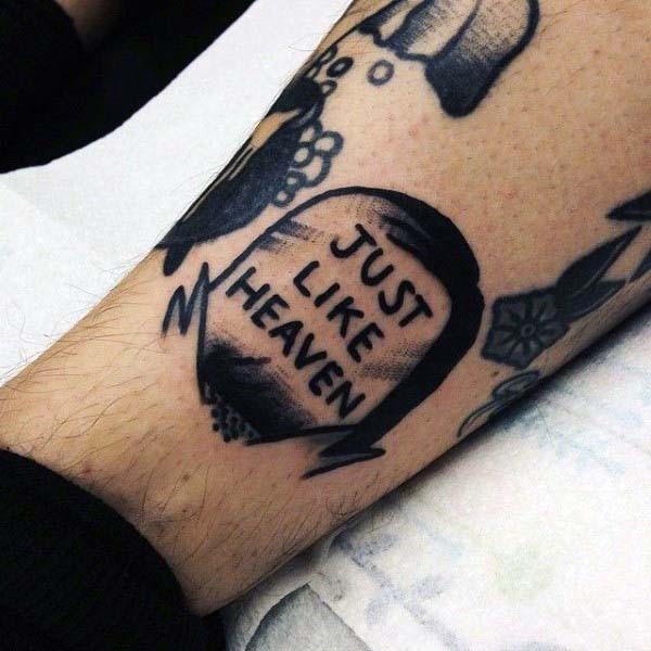Kleines hausgemachtes Tattoo schwarzer Grabstein mit Schriftzug am Arm