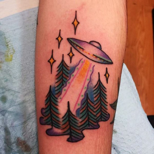 Little multicolored alien ship with forest tattoo on arm