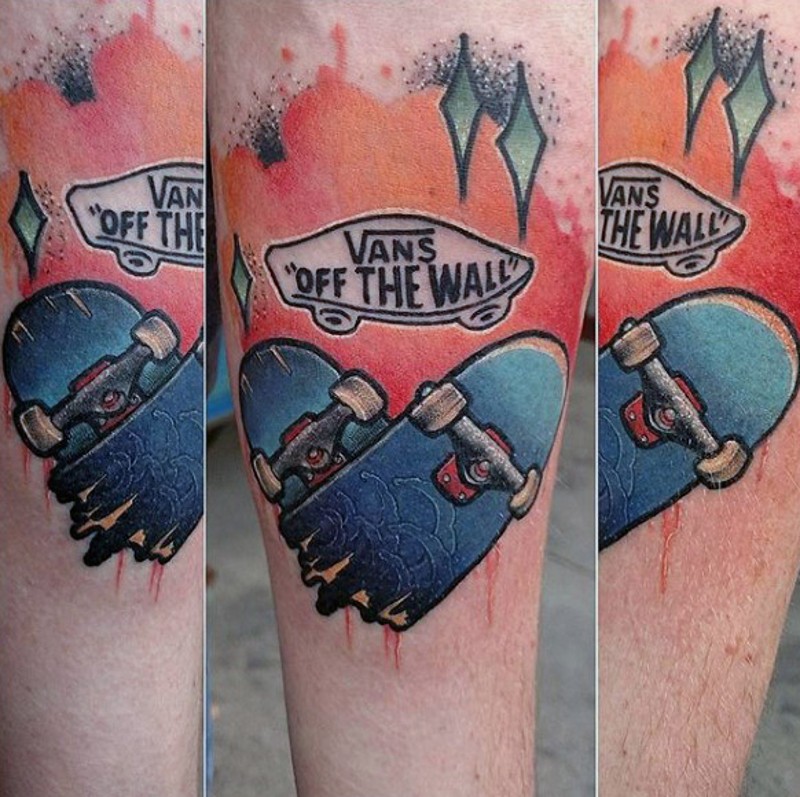 Kleiner mehrfarbiger gebrocher Skateboard mit Schriftzug Tattoo am Arm