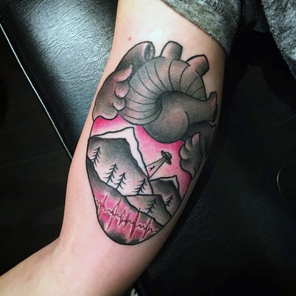 Little multicolored cartoon like heart stylized with alien ship tattoo on arm