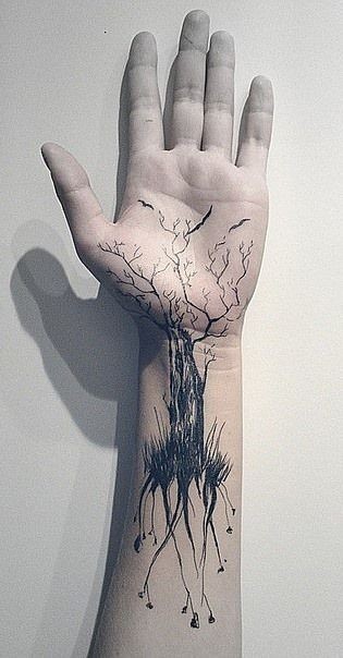 Tatuaje en la muñeca, árbol con raíces largas y ramas con aves, tinta negra