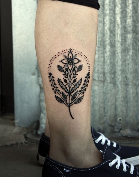 Little very beautiful black ink flower tattoo on leg muscle