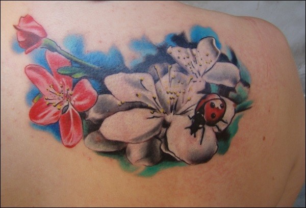 Tatuaje en el hombro, mariquita  y las flores suaves
