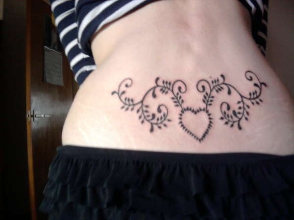 Tatuaje en la espalda baja, corazón y tallo con hojas, dibujo sencillo