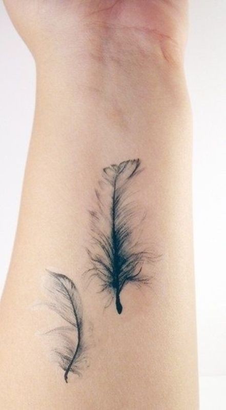 Süßes Tattoo von zwei luftigen Federchen  am Unterarm
