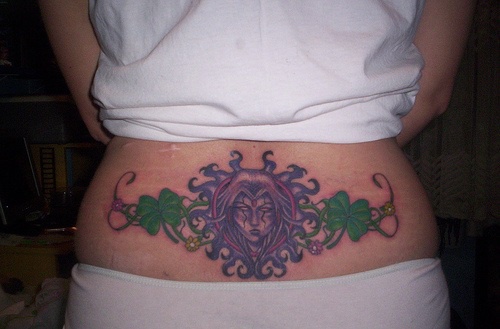 Lower back tattoo black, crying devil woman, styled, clovers