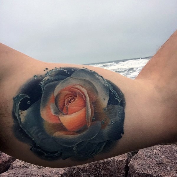 Magical colored little realistic rose with water tattoo on arm
