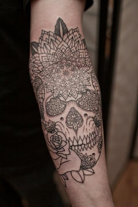 Magnificent black ink detailed human skull tattoo on forearm combined with ornamental flowers