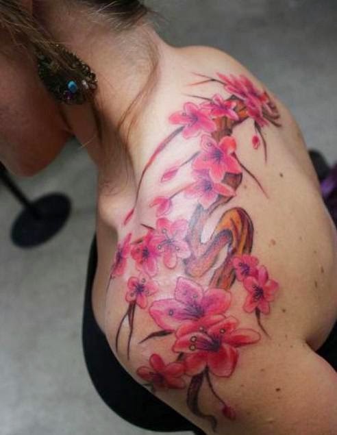 Magnificent pink flowers on branch tattoo on lady&quots shoulder