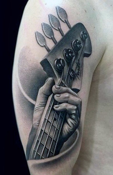 Tatuaje en el brazo, mano de músico que  toca la guitarra