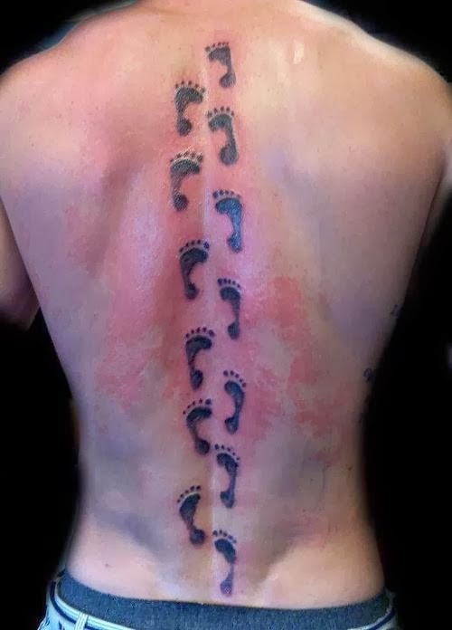 Tattoo von vielen dunklen Babys Fußabdrucken auf dem Rücken