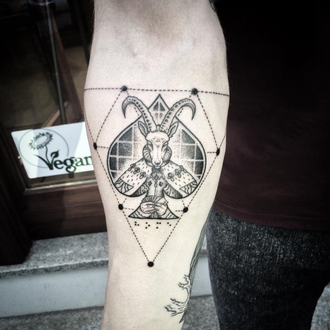 Marvelous black ink mystical goat tattoo on forearm with spades symbol