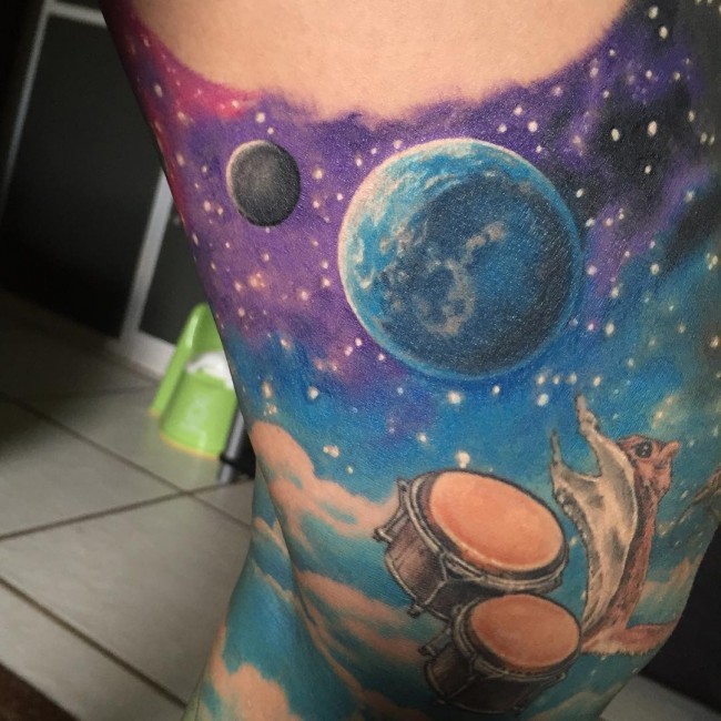 Marvelous colored space tattoo on arm stylized with drums and squerel