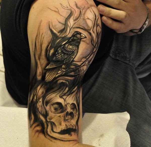 Marvelous painted black and white detailed crow tattoo on shoulder with human skull