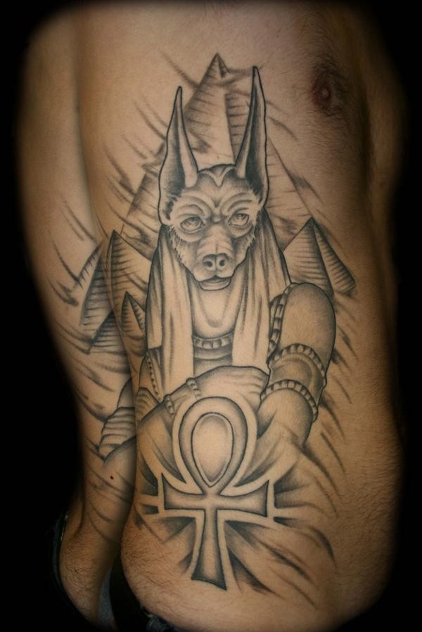 Massive black ink side tattoo of Anubis God and pyramids