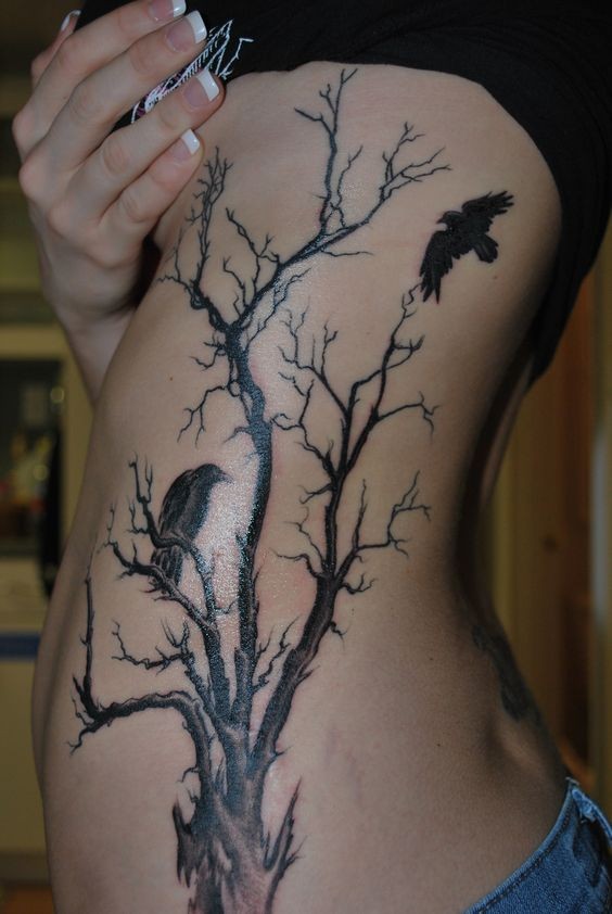 Tatuaje en el costado,  árbol seco alto y dos cuervos