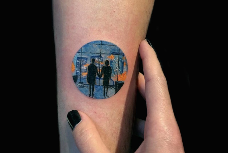 Medium size colored circle shaped tattoo stylized with couple in night city