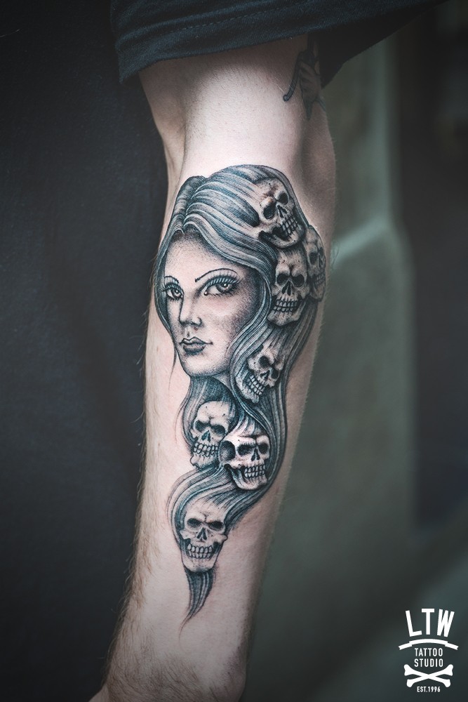 Medium size simple painted and colored arm tattoo of woman stylized with human skulls