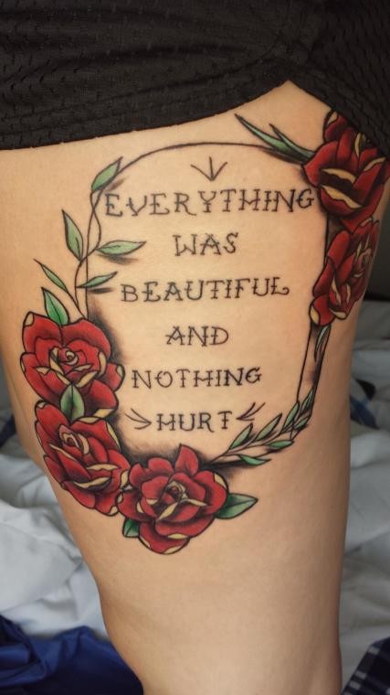 Tatuaje en el muslo,  lápida mortuoria con cita y rosas