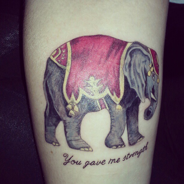 Tatuaje en el brazo,
elefante con chal rojo y cita