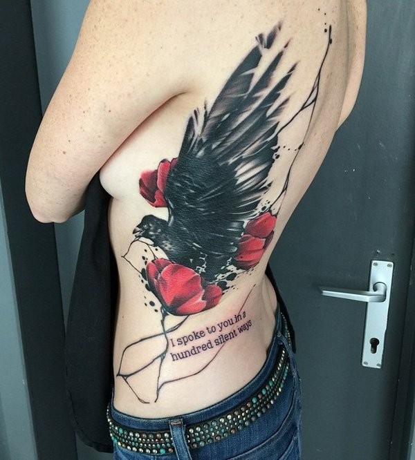 Memorial style painted colored crow with flowers and lettering tattoo on waist and back