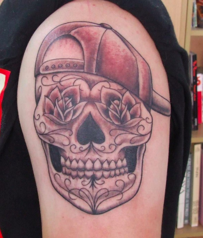 Mexikanischer Stil lächelnder Schädel in der Baseballmütze lustige Idee des Schulter Tattoos