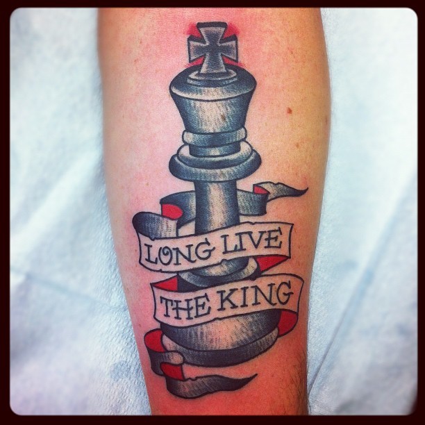 Modern style colored arm tattoo of big chess figure and lettering