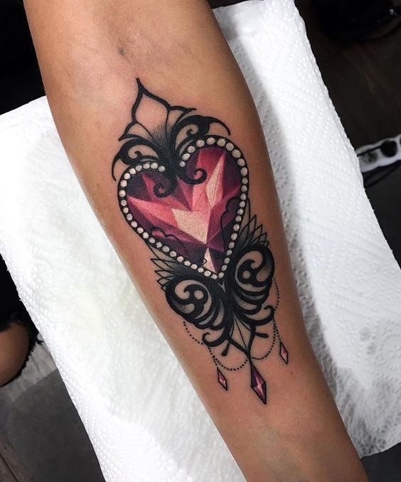 Modern style colored forearm tattoo of heart shaped diamond painted by Jenna Kerr
