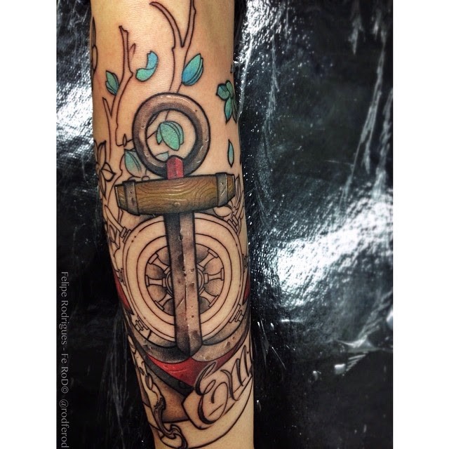 Modern traditional style colored arm tattoo of of anchor with steering wheel