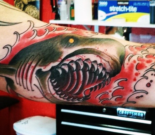 Monster bloody shark with sharp teeth in bloody waves colored tattoo on biceps in old school style