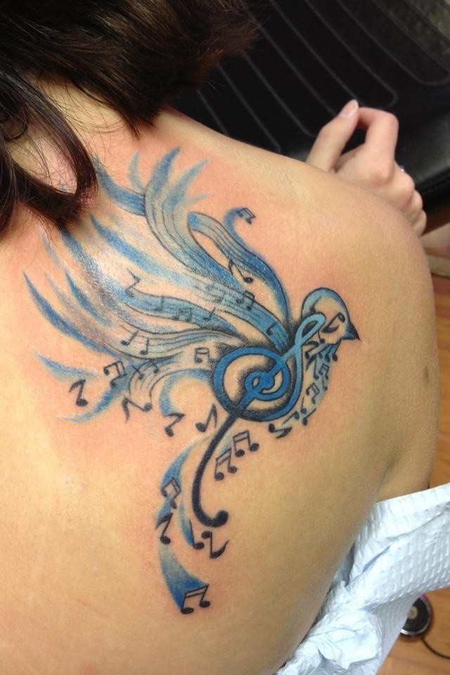 Tatuaje en el hombro, ave formado de notas y clave de sol