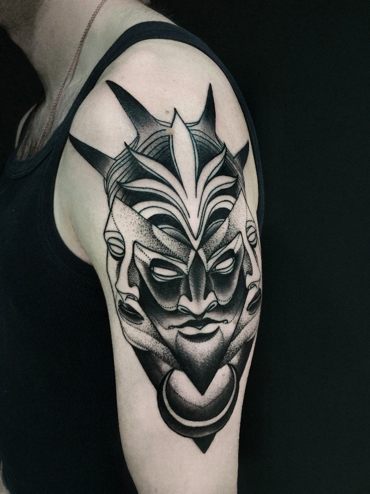 Mysterious blackwork style upper arm tattoo of demonic face by Michele Zingales