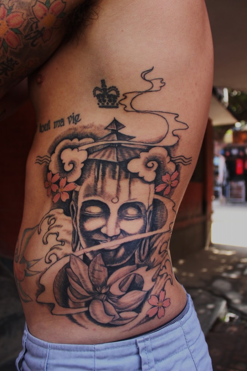 Mysterious colored Asian statue tattoo on back with flowers and steam