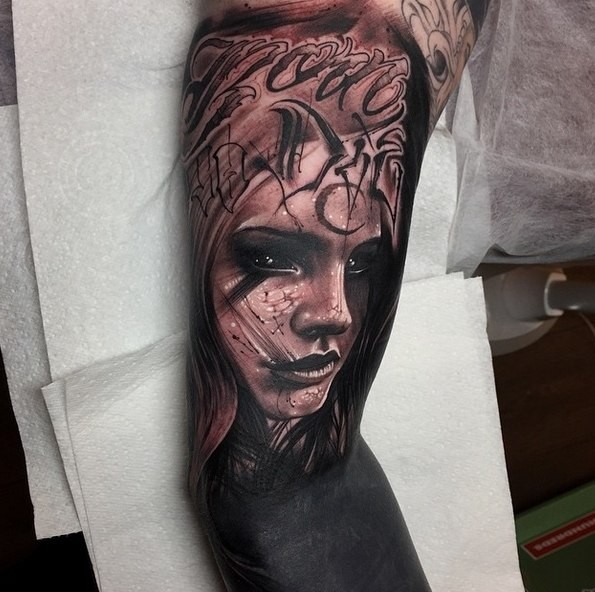 Mystical dark black and gray style colored biceps tattoo of woman and lettering