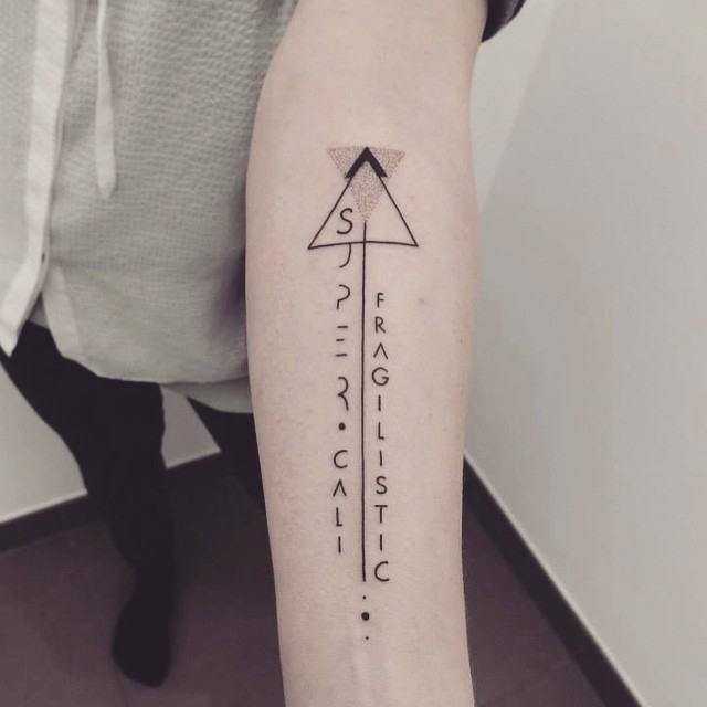 Mystical looking black ink forearm tattoo of geometrical figure with lettering