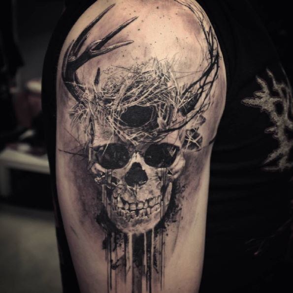 Mystical looking black ink shoulder tattoo of human skull with horns and birds nest