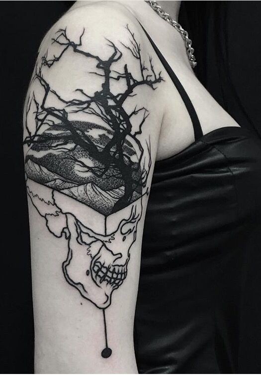 Mystical looking black ink shoulder tattoo of human skull with tree and mountains