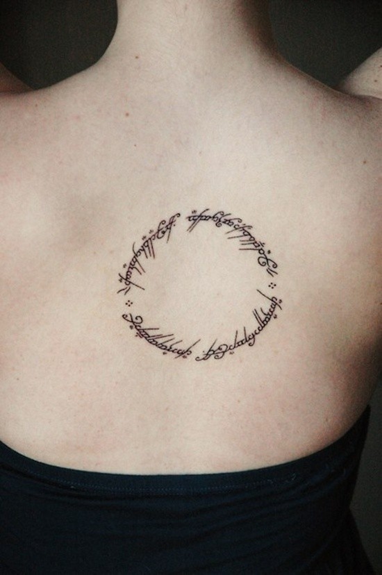 Mystique circle shaped unusual symbolic lettering thin black ink upper back tattoo