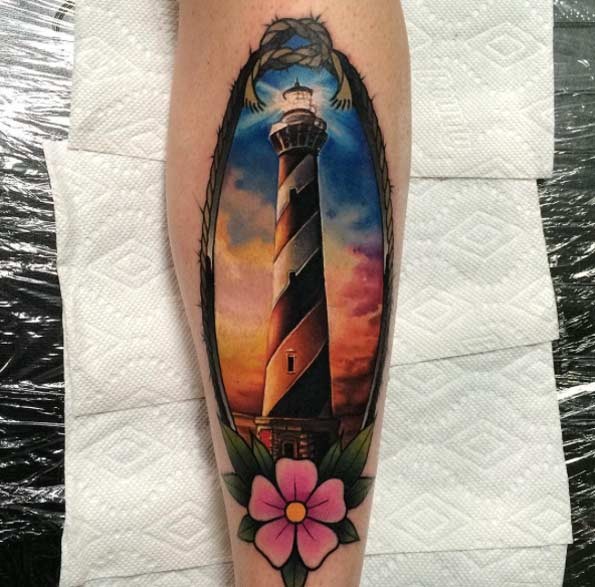 Natural looking beautiful colored big lighthouse tattoo combined with pink flower