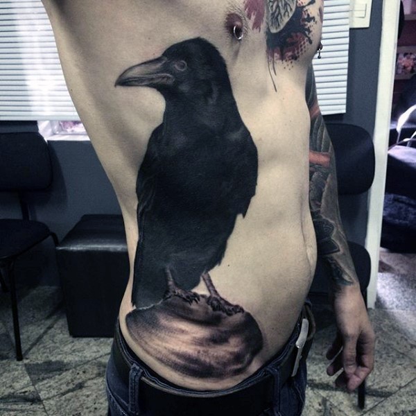 Natural looking big side tattoo of dark crow with stone