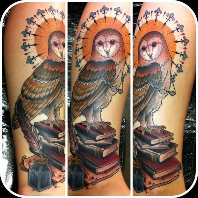 Natural looking colored wise owl tattoo on arm with books