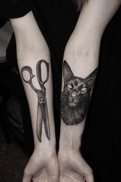 Natural looking demonic cat tattoo combined with scissors on forearms