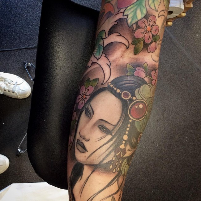 Natural looking multicolored forearm tattoo of Asian woman and flowers