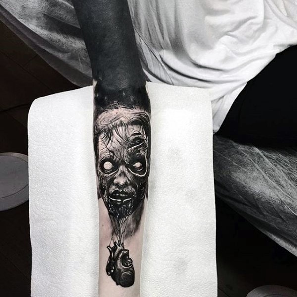 Natural looking very detailed forearm tattoo of zombie head combined with human heart