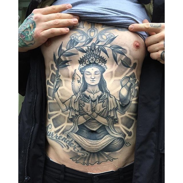 New school style black ink painted by Michael J Kelly chest and belly tattoo of Buddha with lettering