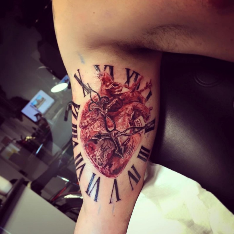 New school style colored biceps tattoo of human heart and clock