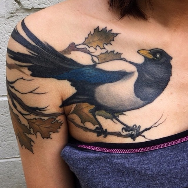 New school style colored bird tattoo on chest with tree branch and leaves