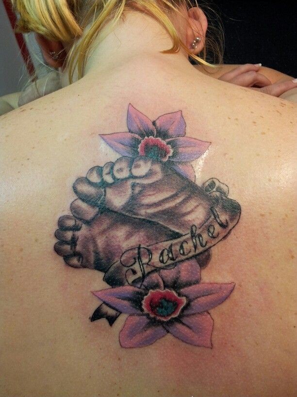 bei piedi di bambino con fiori rosa e nome tatuaggio su schiena