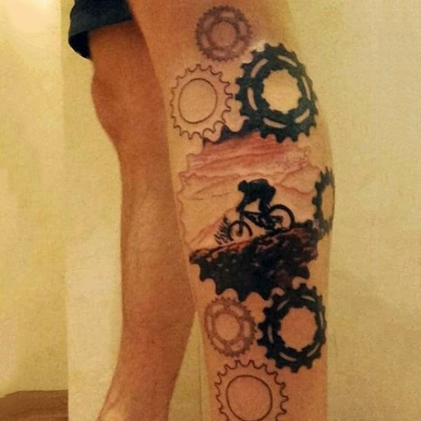 Tatuaje en la pierna, ciclista en montañas y montón de mecanismos