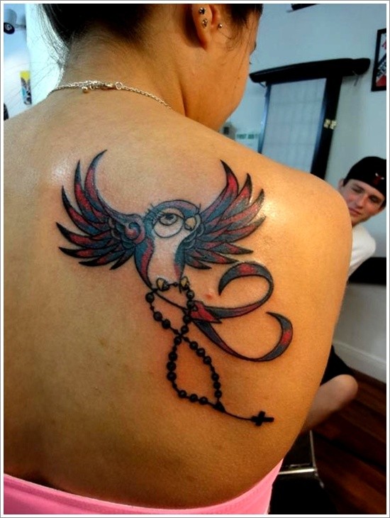 Tatuaje en la espalda, ave que lleva la cruz
